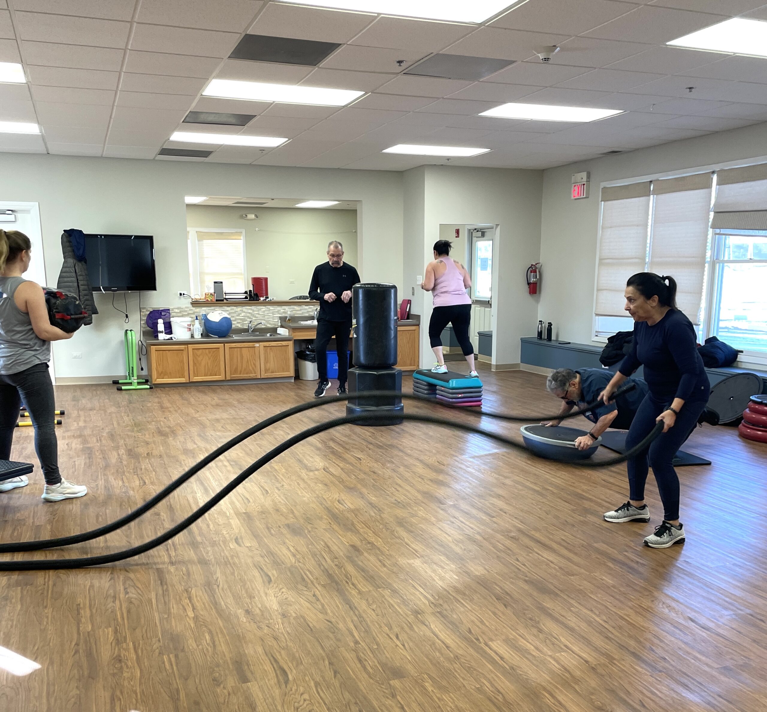 People work out in a room using various fitness equipment.